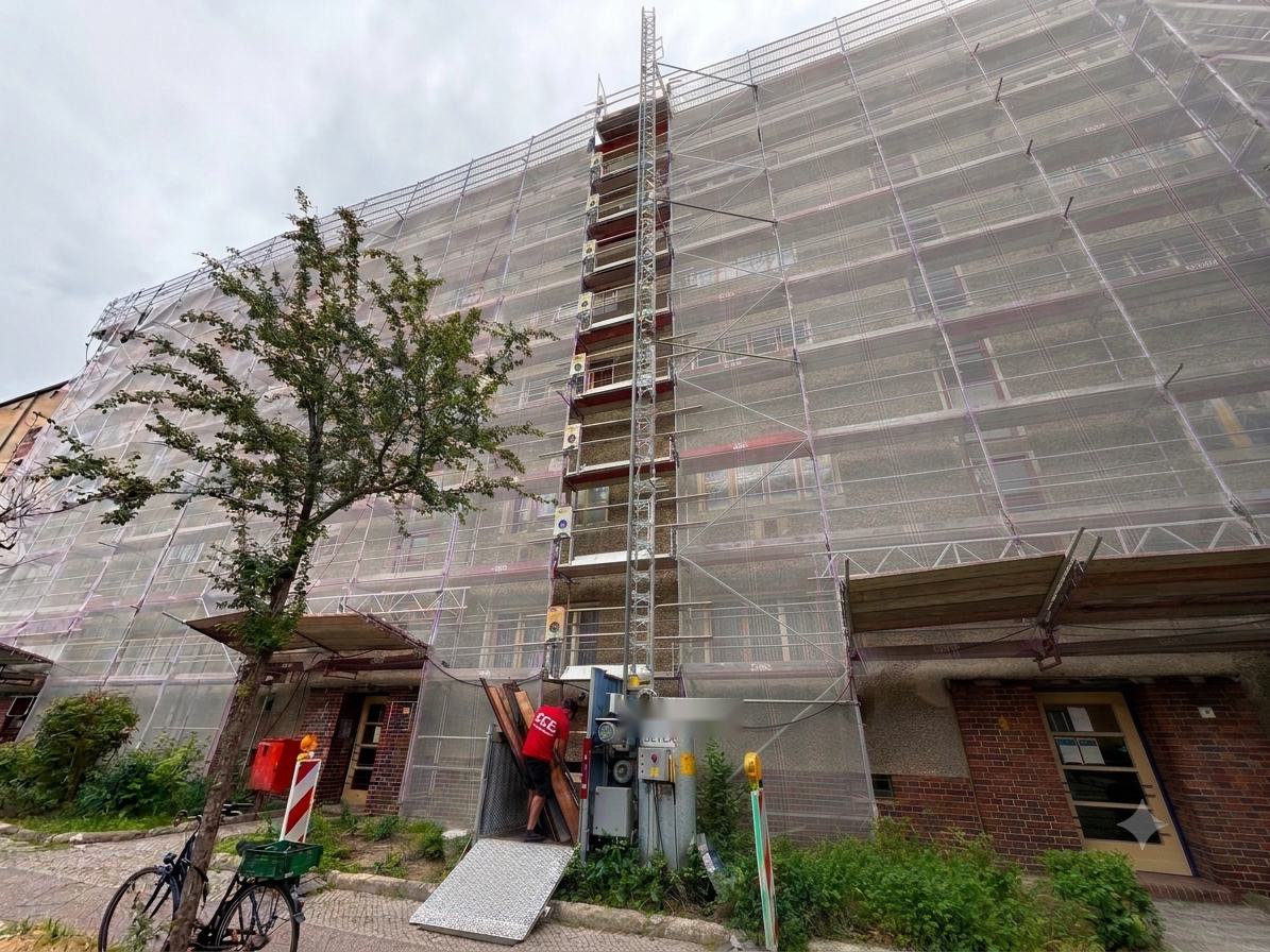 Mitarbeiter transportiert Bretter der zurückgebauten Holzschalung über den Bauaufzug ab
