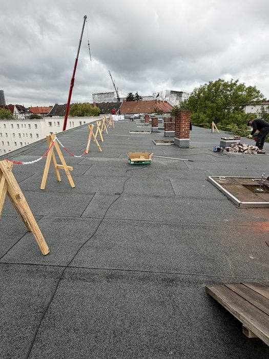 Flachdach mit abgesperrtem Arbeitsbereich während des Schornsteinabbruchs